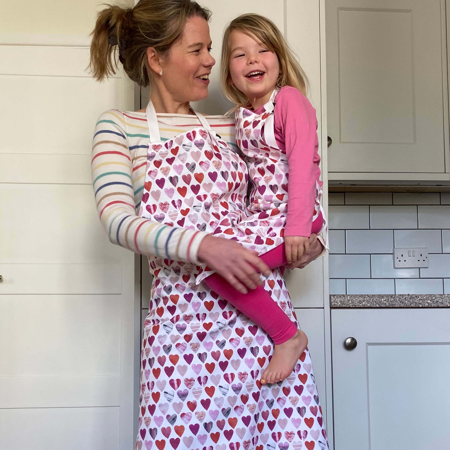 Model wears hearts apron with a white background with pink and red hearts.