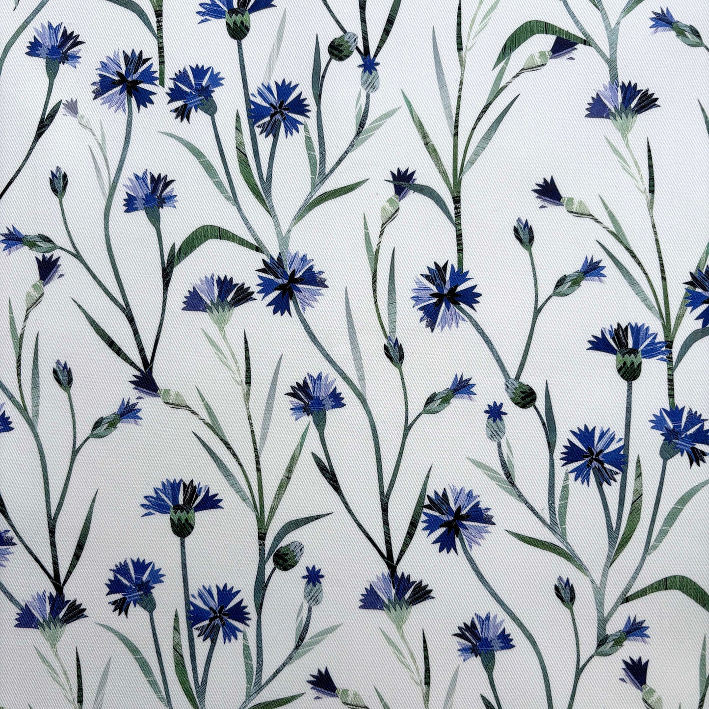 Close up of the blue cornflower pattern with green leaves on an off white background.