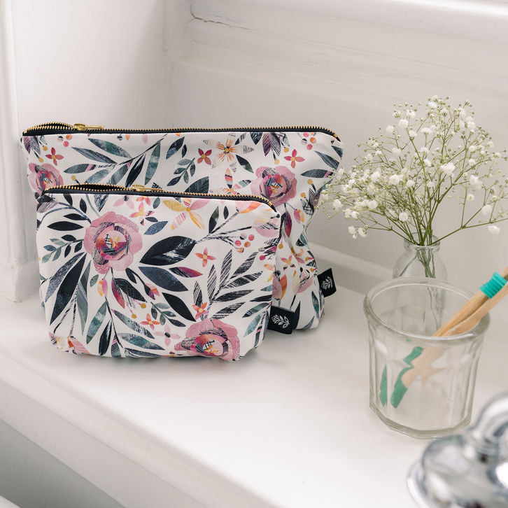 Summer Floral-patterned pouch on a bathroom counter with a glass of water and toothbrushes.