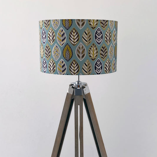 Large Blue Beech leaf Lampshade, shown here on a wooden tripod floor lamp.  The pattern features a Skandi style Blue, yellow, grey and white Leaf pattern on a Blue Background.