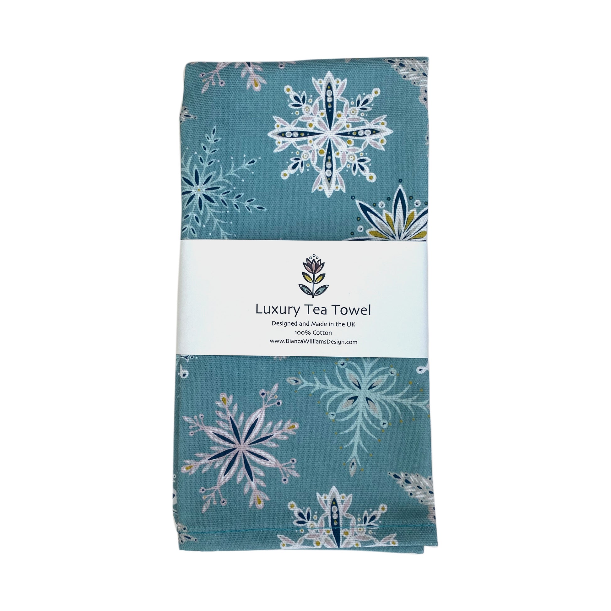 A Blue Snowflake Tea Towel has been packaged in a branded belly band and placed on a white background.