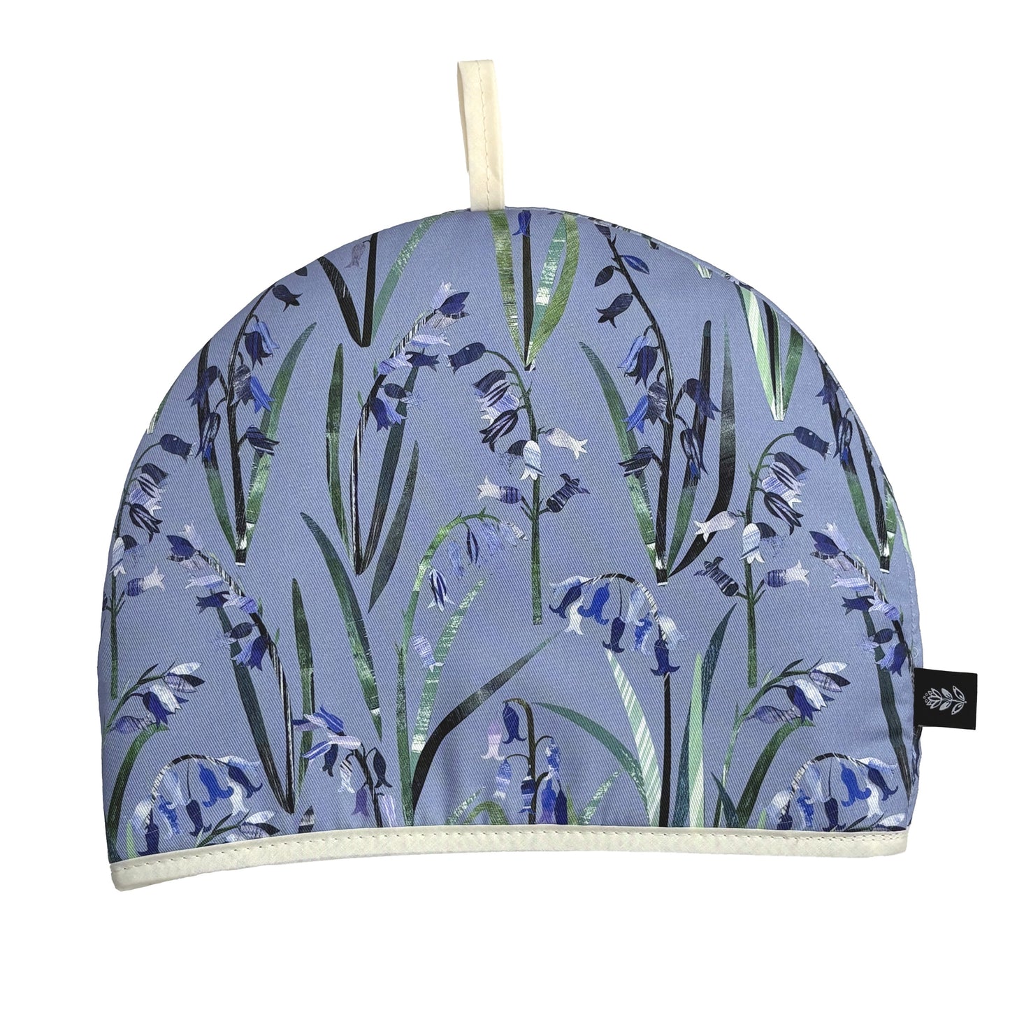 A Tea cosy with a spring floral pattern featuring blue bluebells with green leaves has been put on a white background.