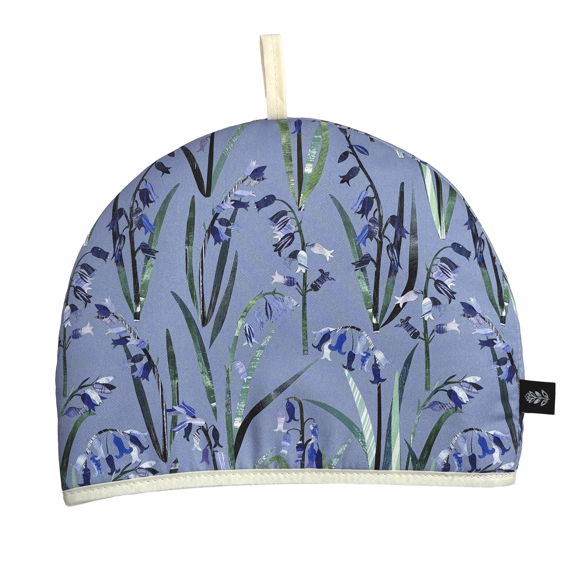 A Tea cosy with a spring floral pattern featuring blue bluebells with green leaves has been put on a white background.