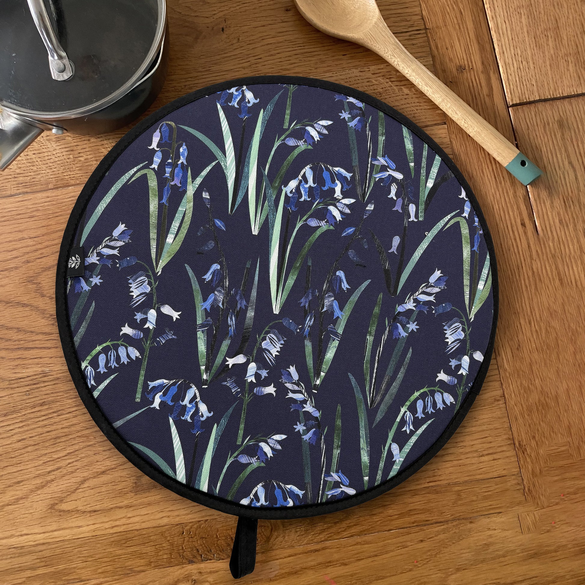 Bluebell Aga Cover has been placed on a wooden table with a saucepan and a wooden spoon.