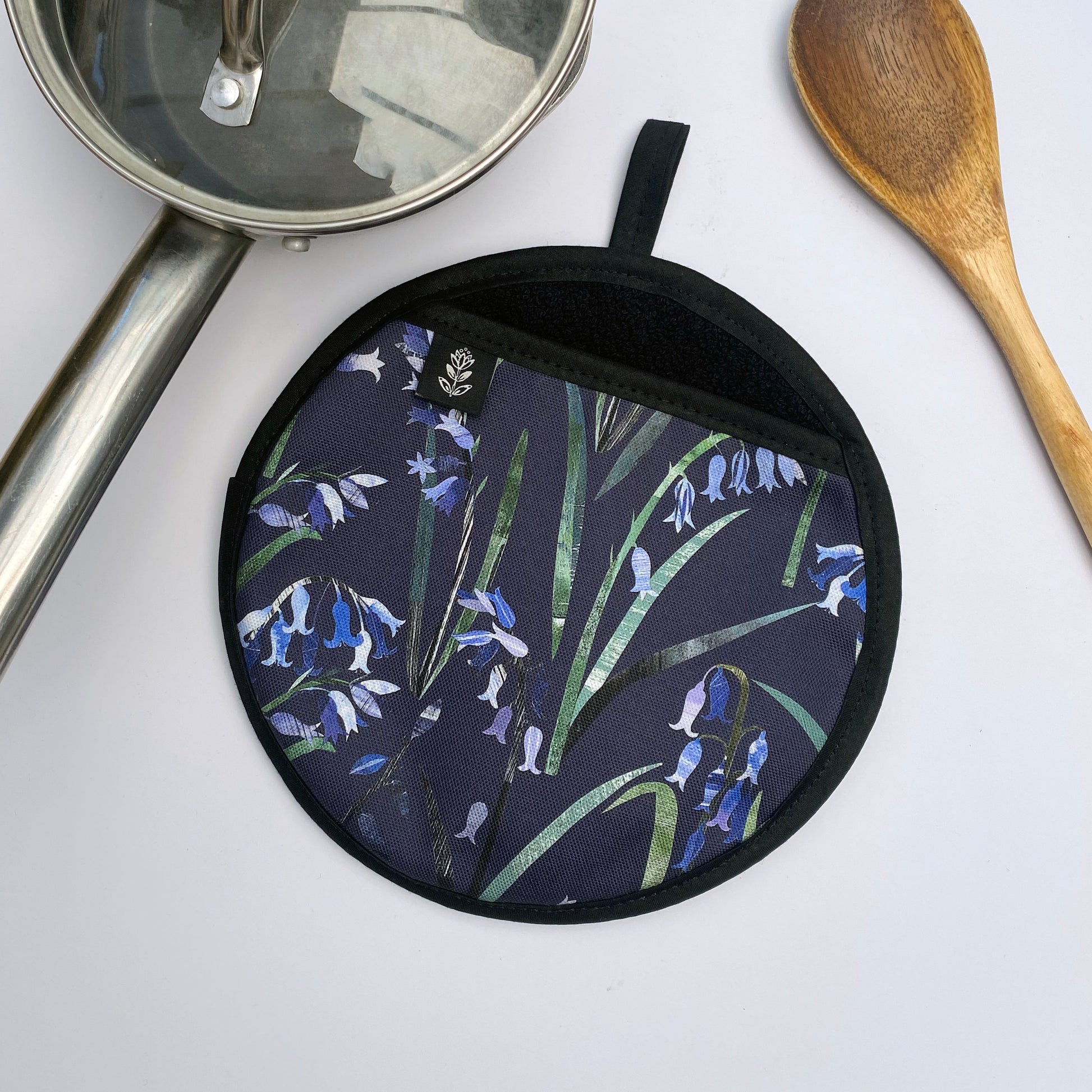 Bluebell pot grab placed on a white background with a wooden spoon and small saucepan.