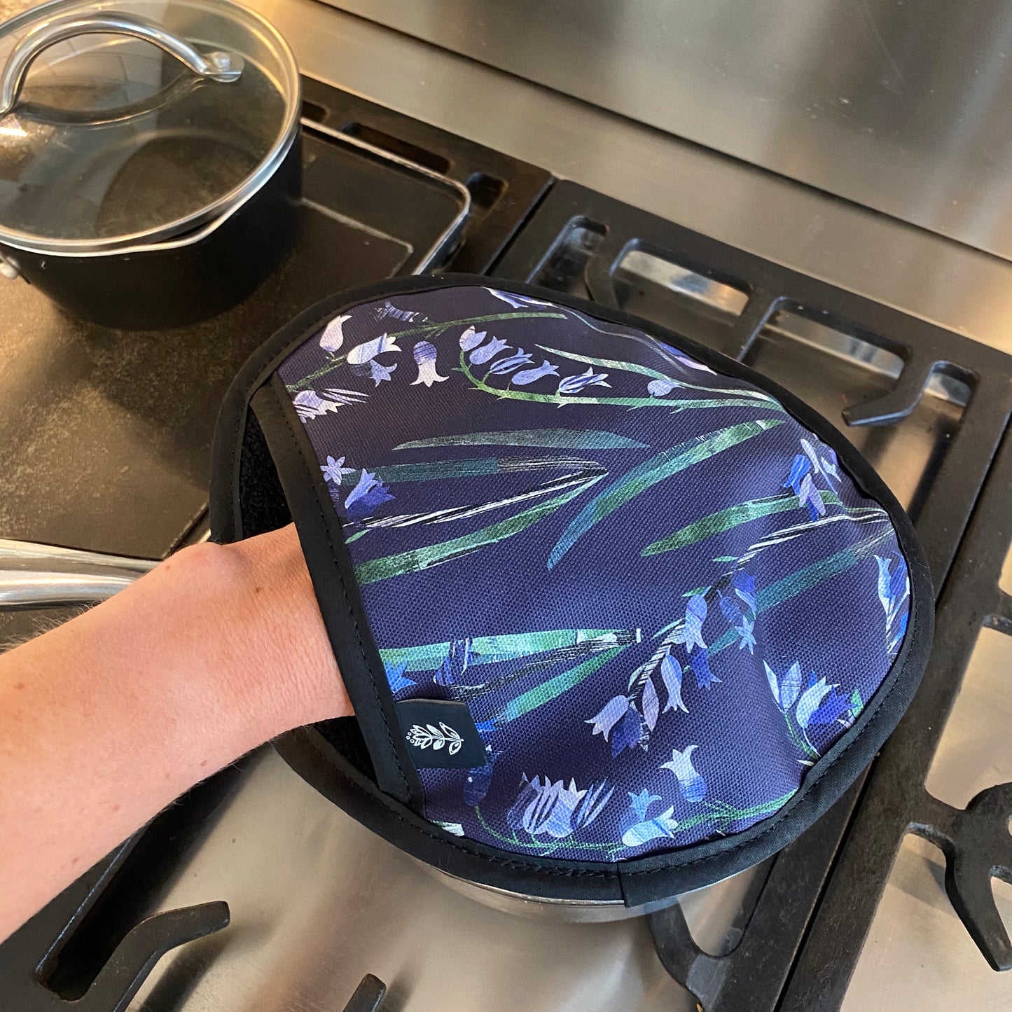 The Bluebell single oven mitt is being used here to remove a hot lid off a saucepan.