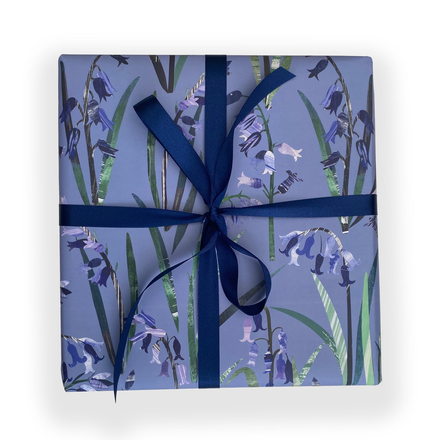 A present has been wrapped in Bluebell Gift Wrap and has been tied with a coordinating dark blue satin ribbon and placed on a plain white background.