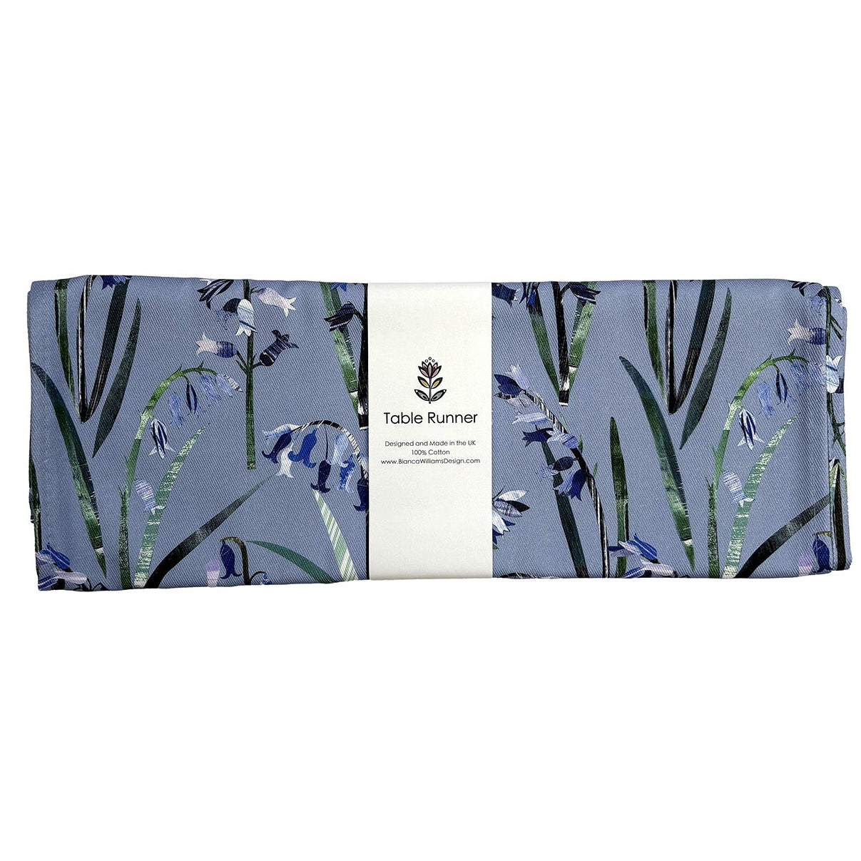 A bluebell table runner has been folded and packaged in a white branded belly band and has been placed on a white background.