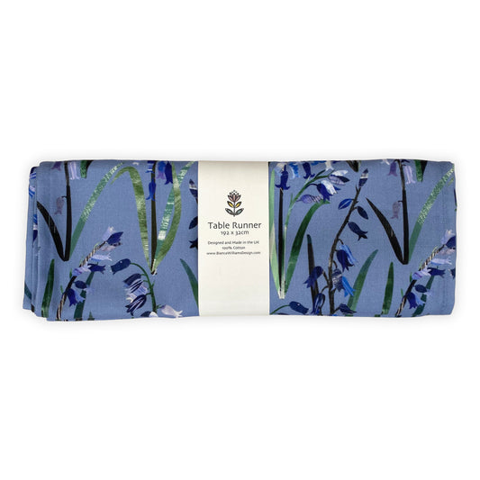 Folded and packaged Bluebell Table Runner.  Packaged in a branded white belly band and placed on a white background.