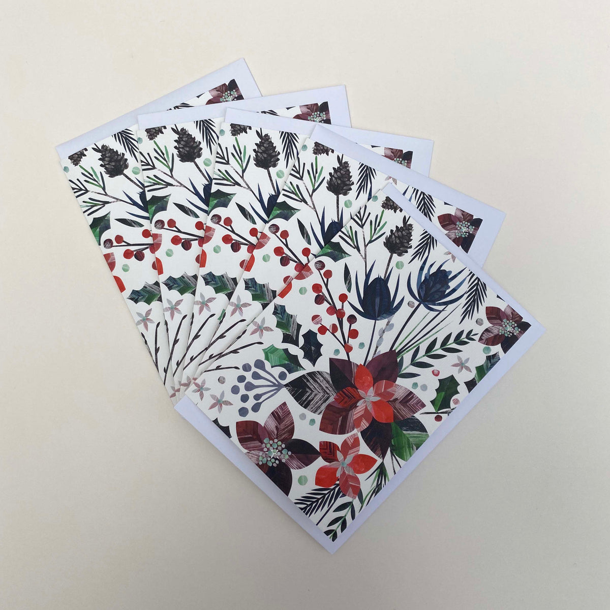 A pack of 5 winter floral christmas cards and envelopes have been fanned out onto a white background.