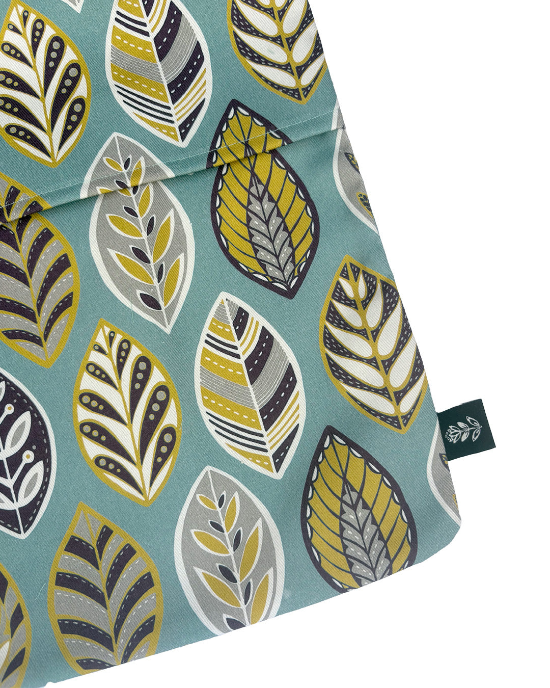 A close up of the Blue leaf Peg bag, you can see the slit to get the peg in and out of it and you can also see the brand label sewn into the outside seam.  It has been placed onto a plain white background.