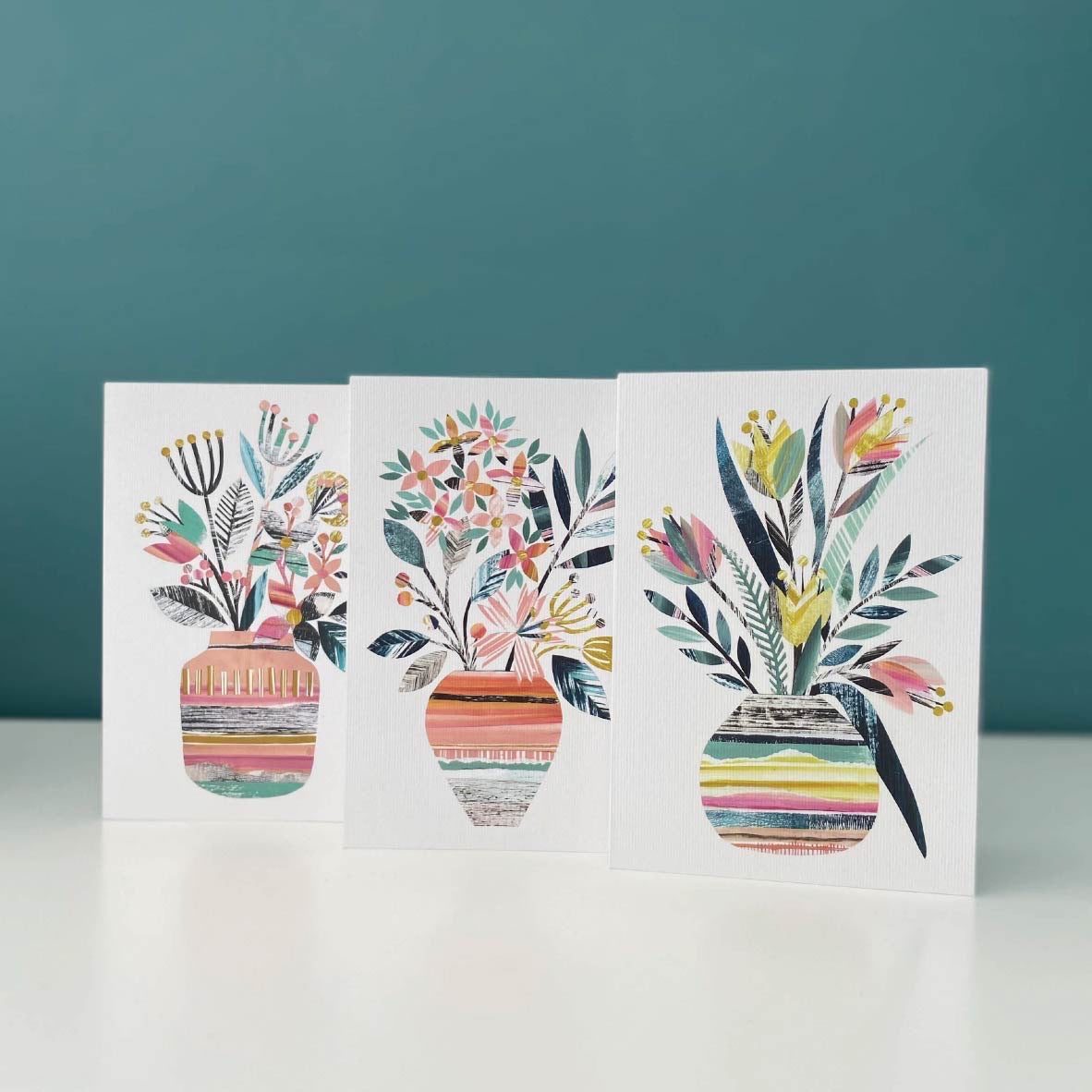 A set of 3 different colourful greeting cards with vases of flowers on them.