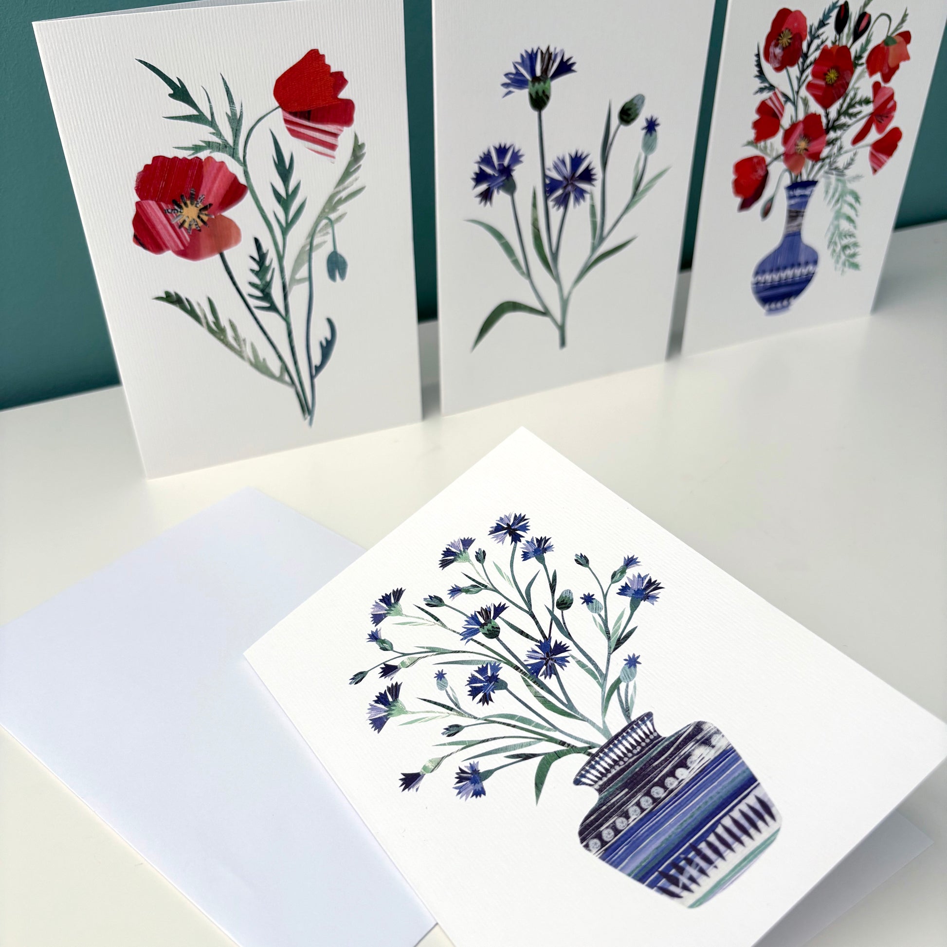 Set of Cornflower and Poppy greeting cards on a white surface.