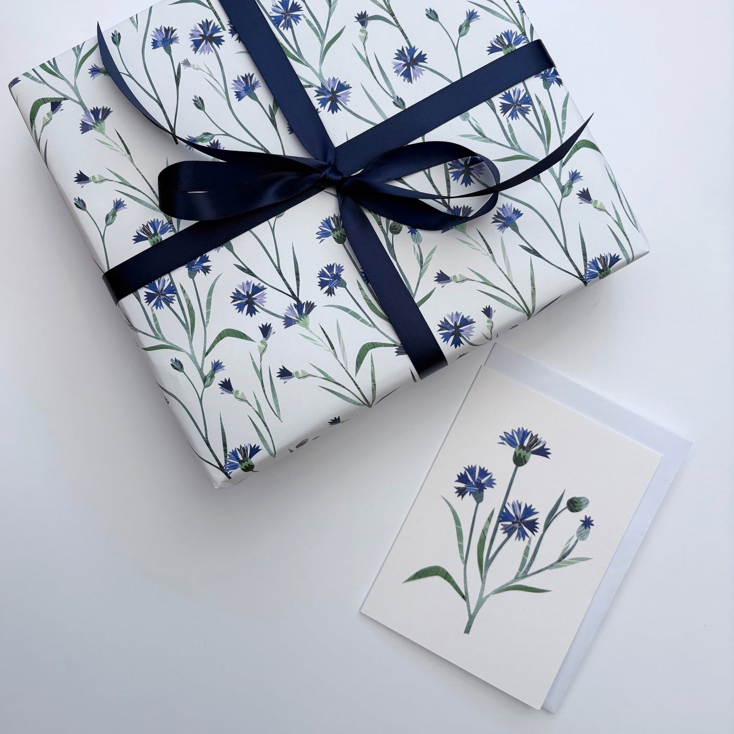 Gift wrapped in Cornflower floral paper with a blue ribbon and a matching Cornflower card on a white background.