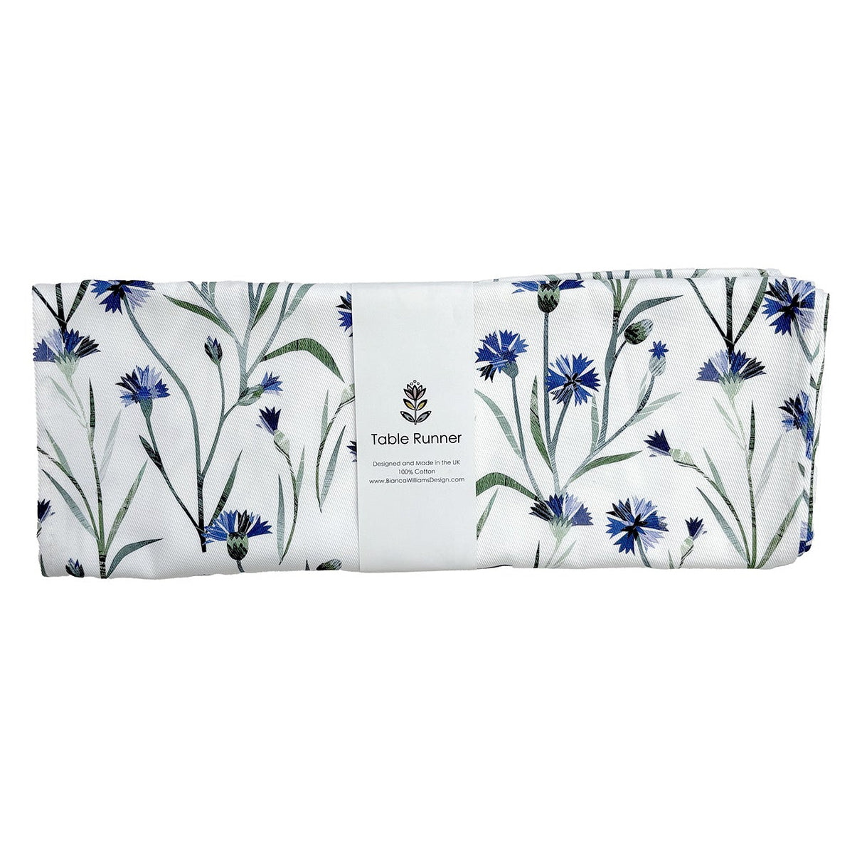 Floral table runner with cornflower design on a white background has been folded up and packaged in a branded belly band and placed on a plain white background.