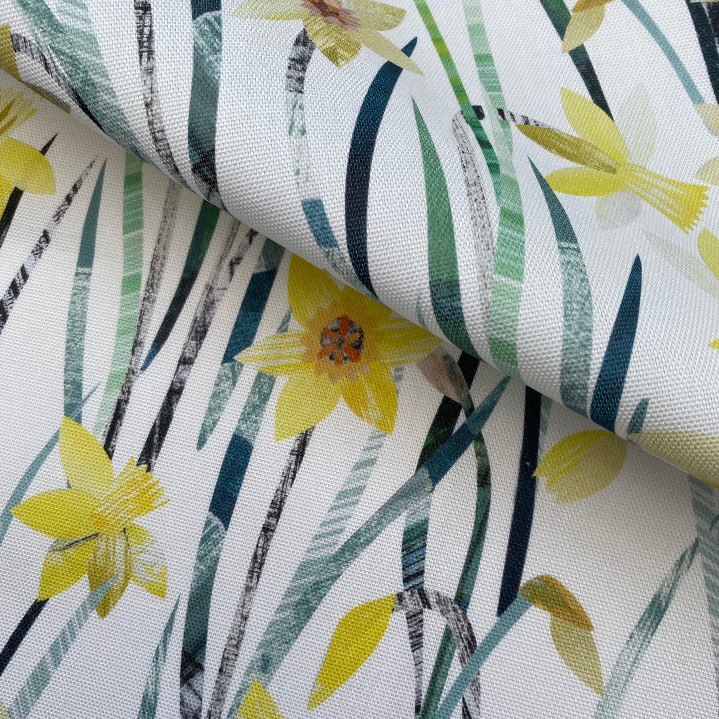 Close up of the Daffodil fabric featuring textured yellow Daffodil flowers with green leaves on a white background.