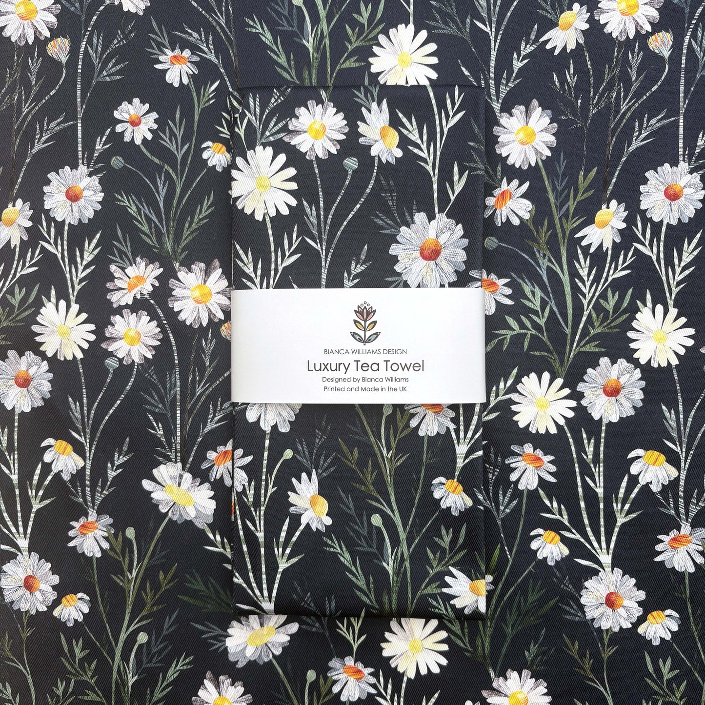 A packaged Daisy Tea Towel has been placed on a lady out tea towel featuring the same Daisy pattern.