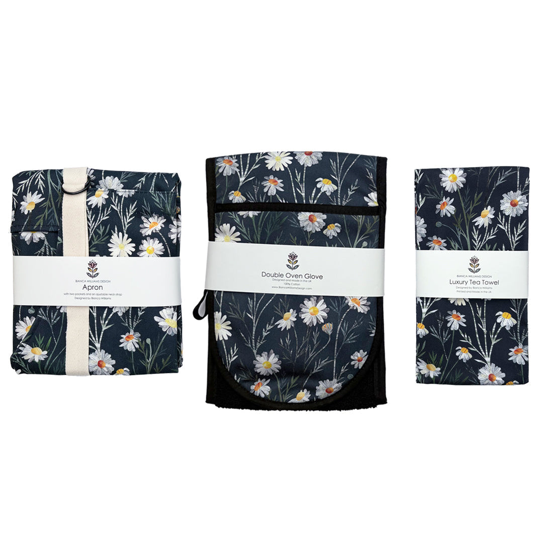 Set of matching Daisy Double Oven Gloves, Tea Towel and Apron, have been packaged and placed on a plain white background.