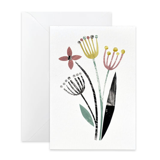 A white textured greeting card with a minimalist botanical illustration of four wildflowers in muted pink, yellow, black, and sage green, shown with a matching white envelope behind it on a light gray background.
