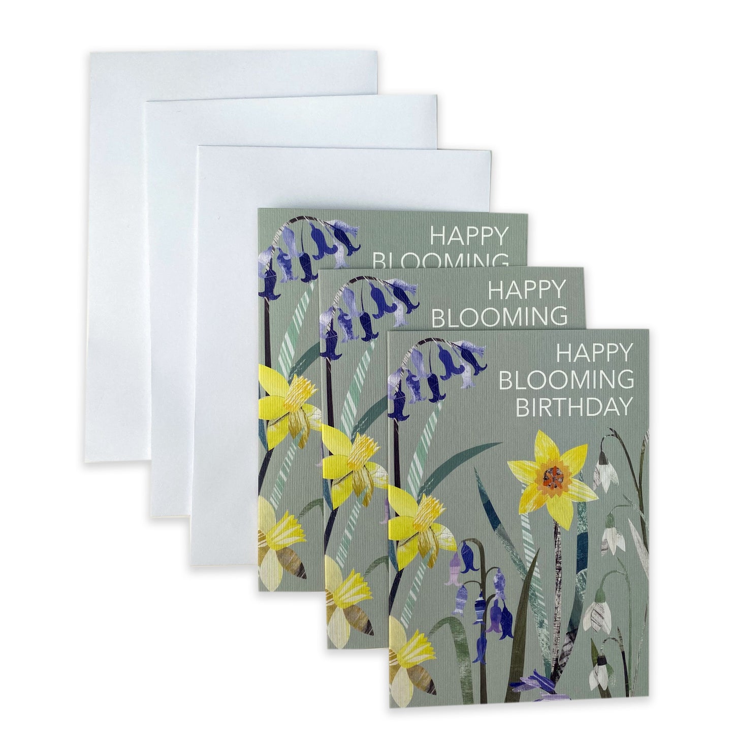 Three Happy Blooming birthday cards and white envelopes have been laid onto of each other on a plain white background.