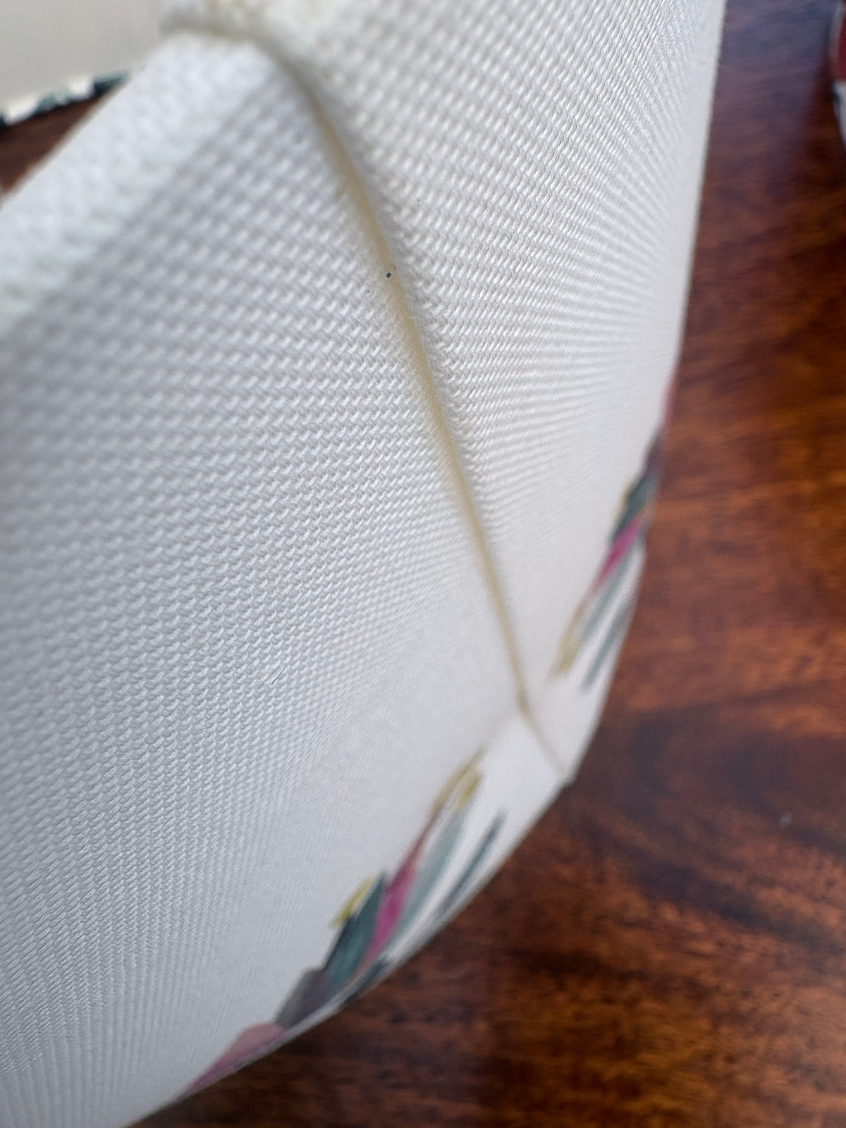 Close-up of a white textured back of lampshade, resting on a dark brown wooden surface.