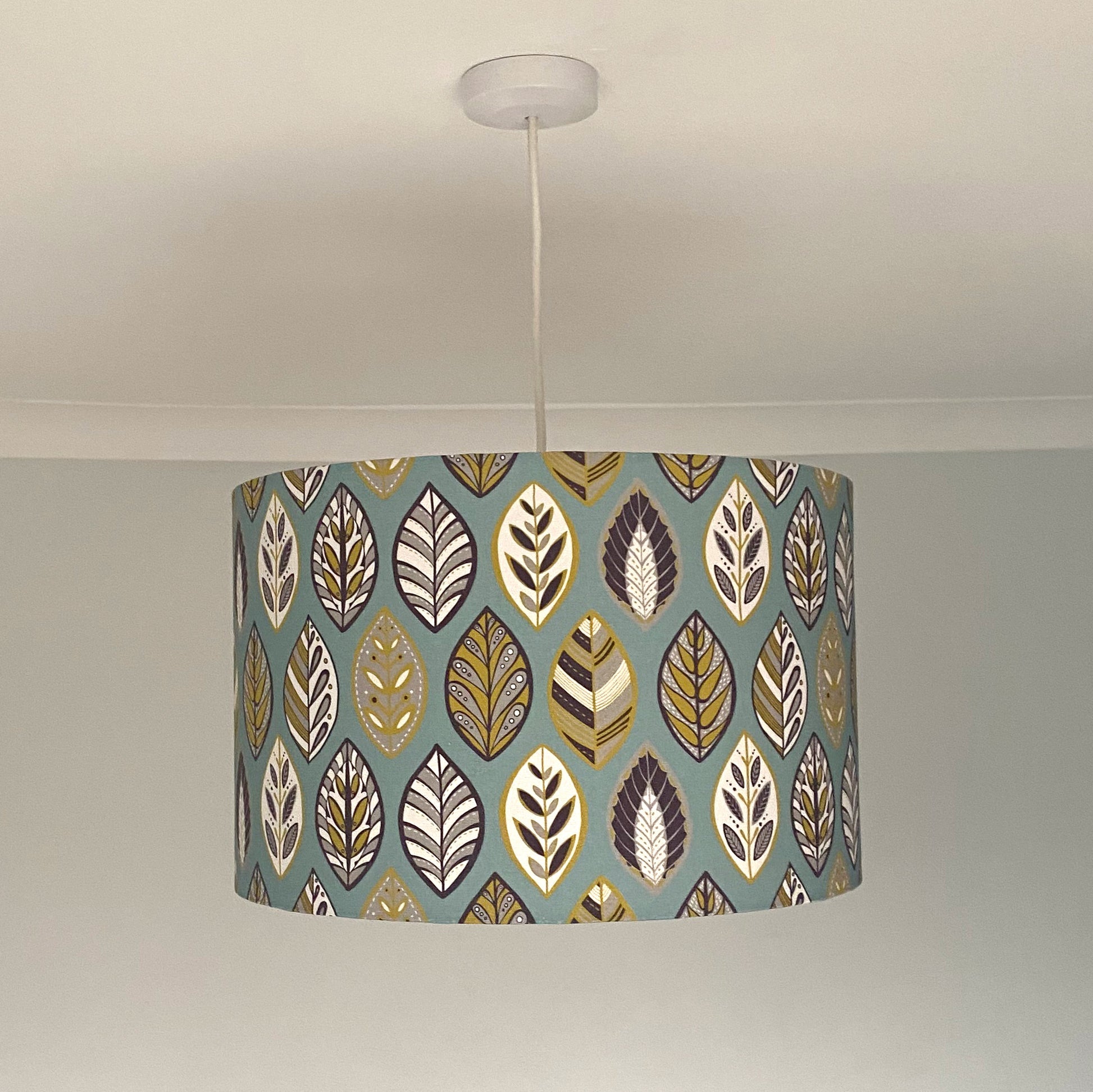 Large Blue Beech leaf Lampshade, shown here on a ceiling pendant. The pattern features a Skandi style Blue, yellow, grey and white Leaf pattern on a Blue Background. Shown with the light switched off.