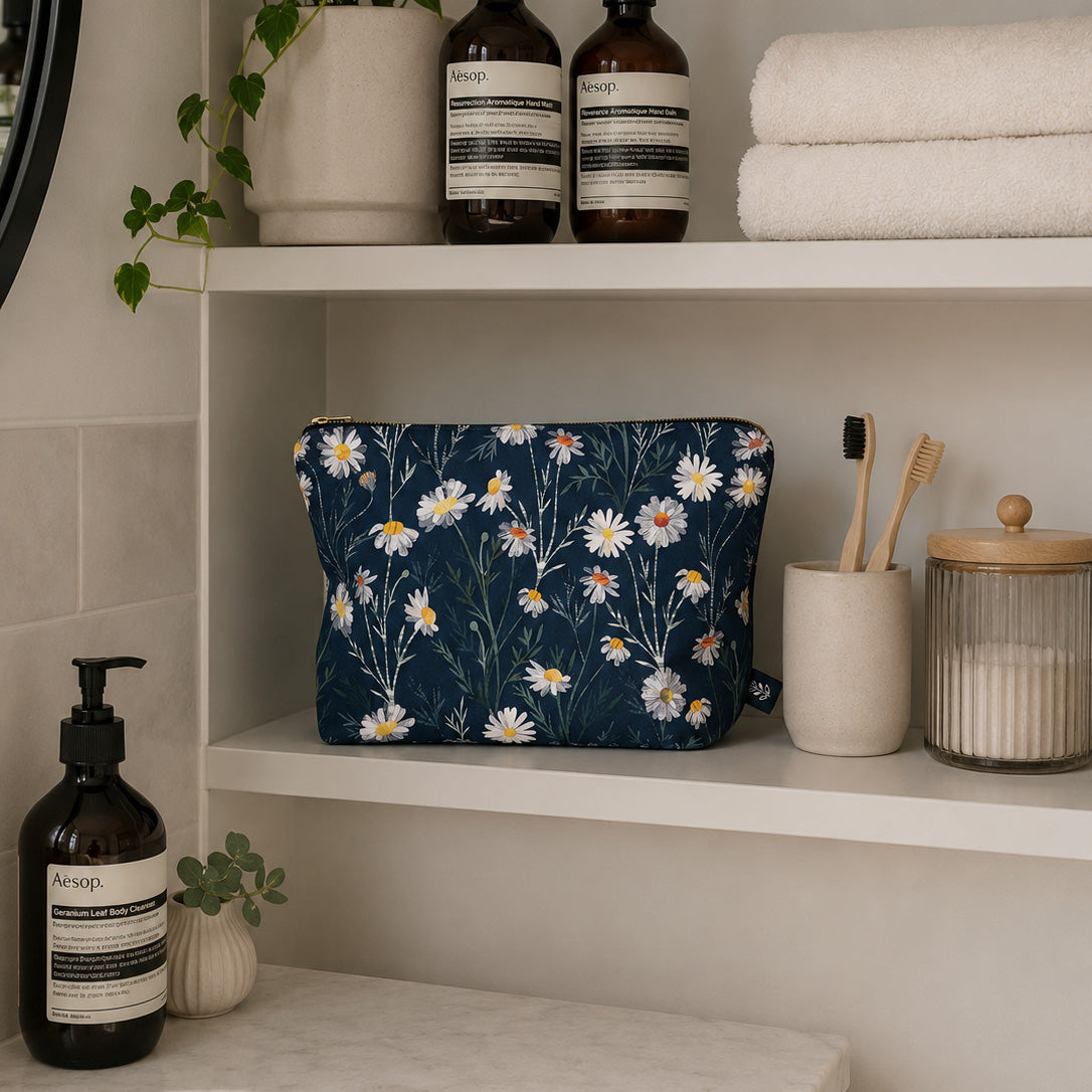 Large Daisy Floral-patterned pouch on a bathroom shelf with Aesop products and towels.