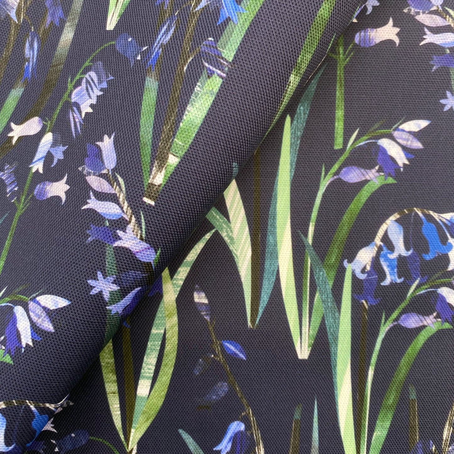 Close up of textured Bluebells with green leaves have been printed onto a Navy Blue cotton background.