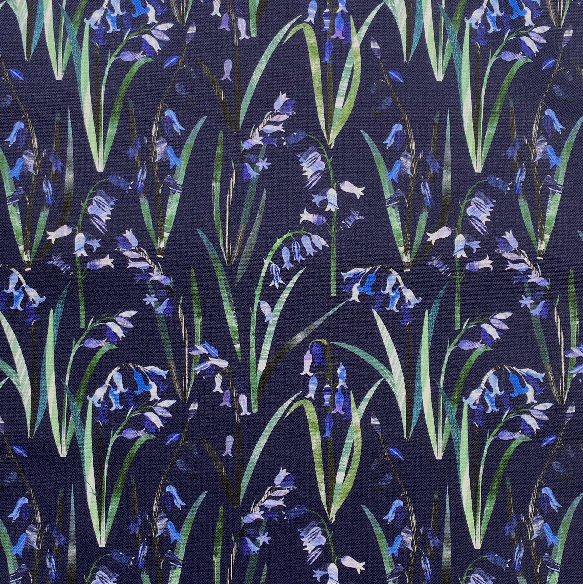 Blue textured Bluebells with green leaves have been printed onto a Navy Blue cotton background.