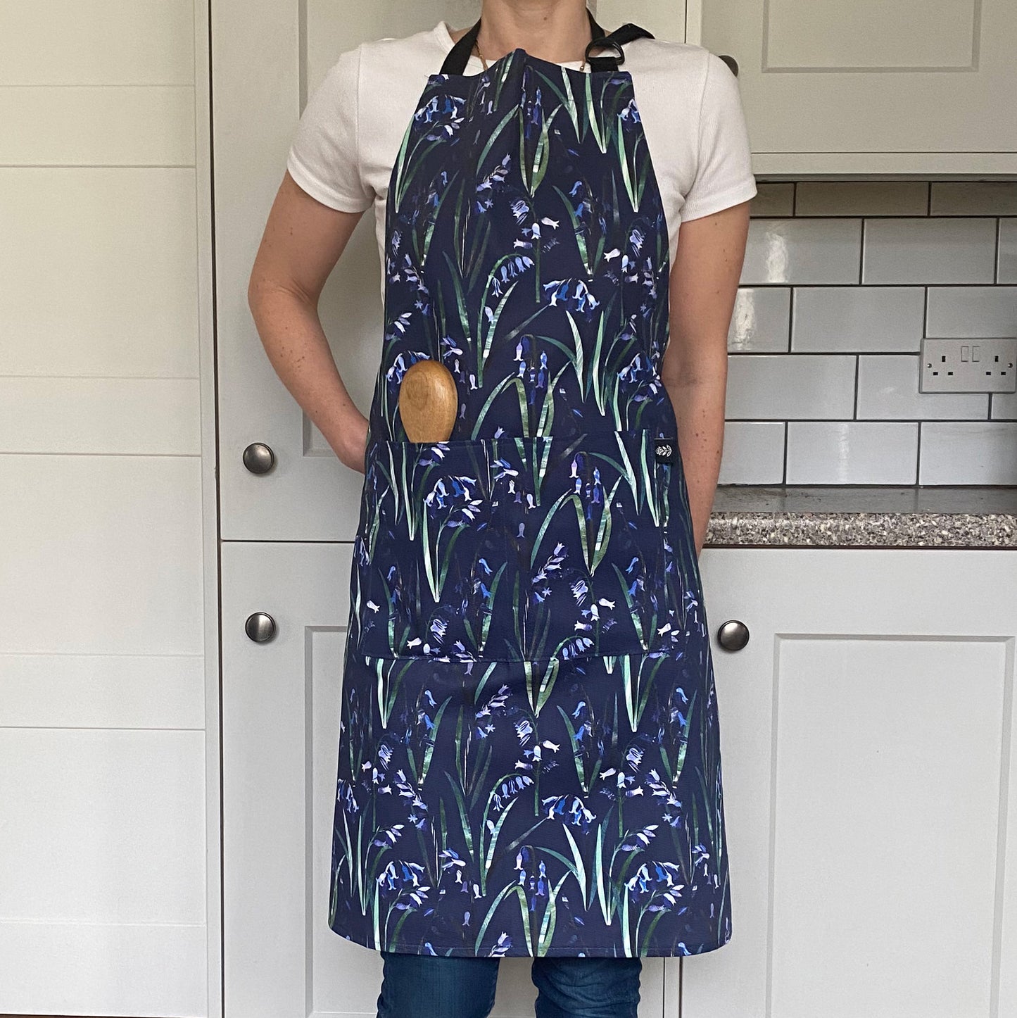 The Model wears the Navy Bluebell Apron, with two front pockets and adjustable neck strap.