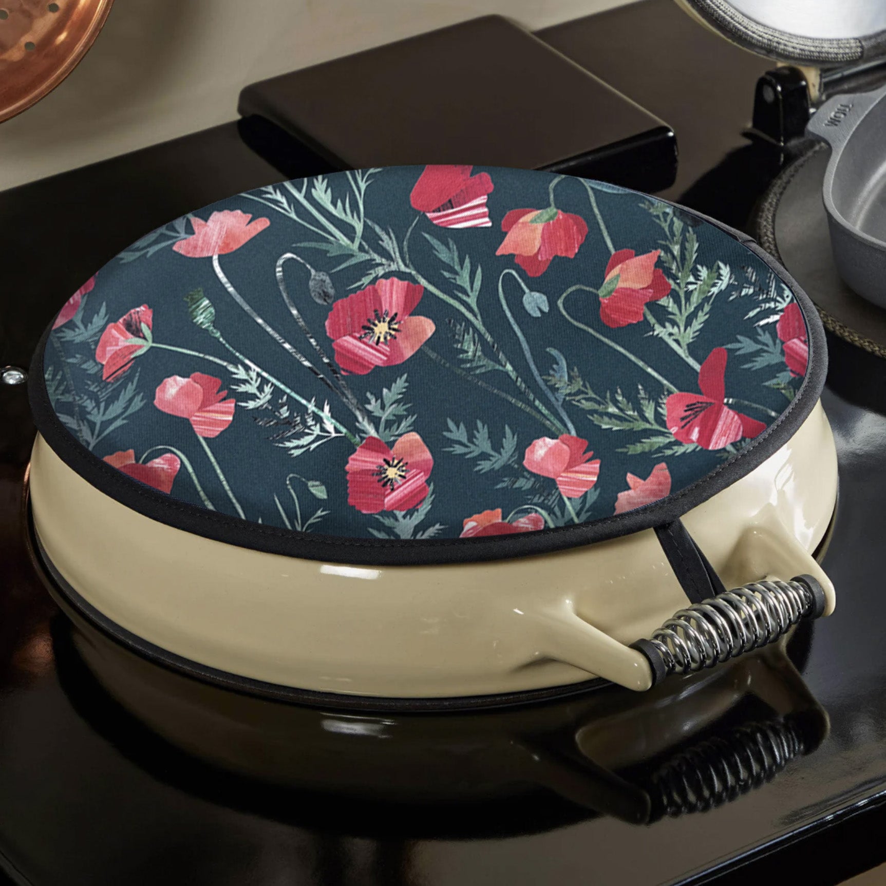 A Red poppy Aga cover has been placed on a black and cream Aga.  it is secured to the Aga using a hook.