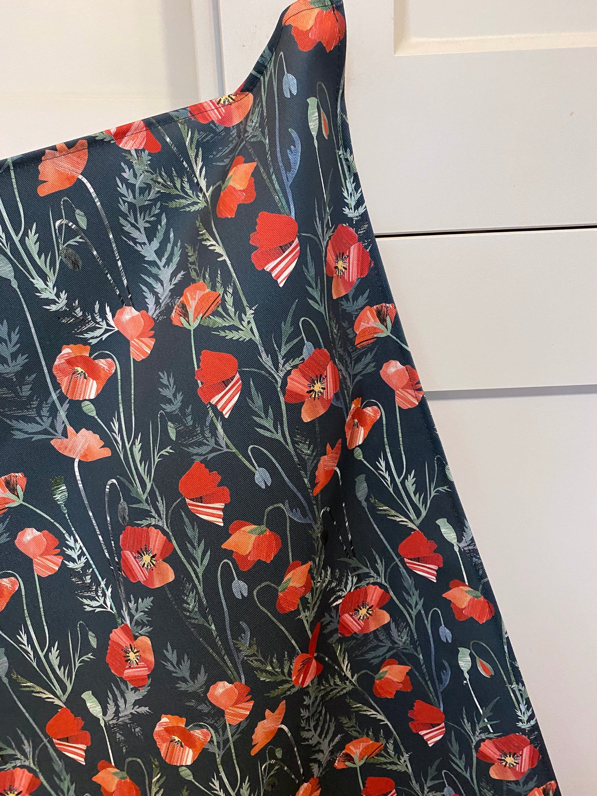 A Poppies tea towel has been Hung on a kitchen door handle.