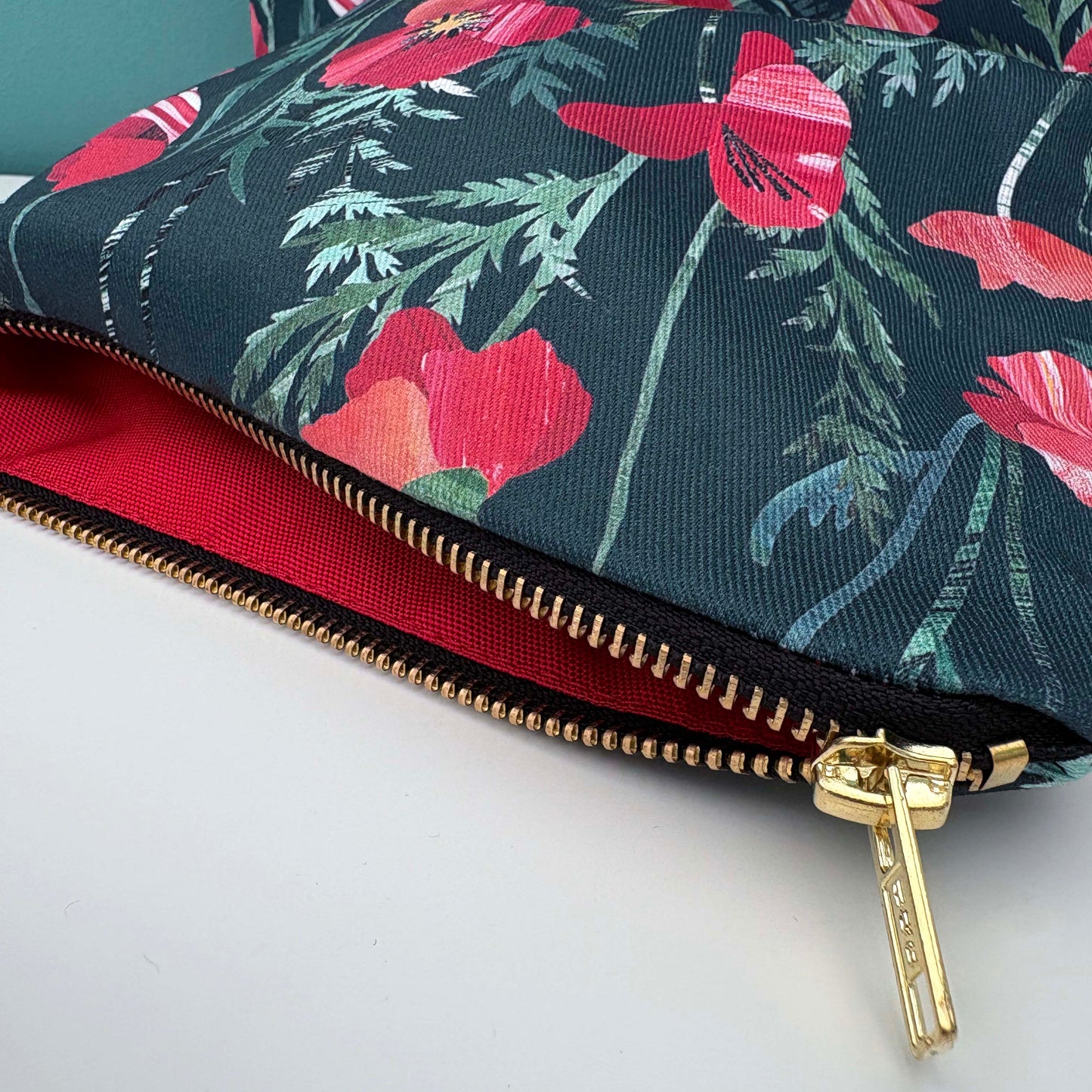 Close up of the poppy make up bag and the gold zipper is open and you can see the bright red poppy lining inside.