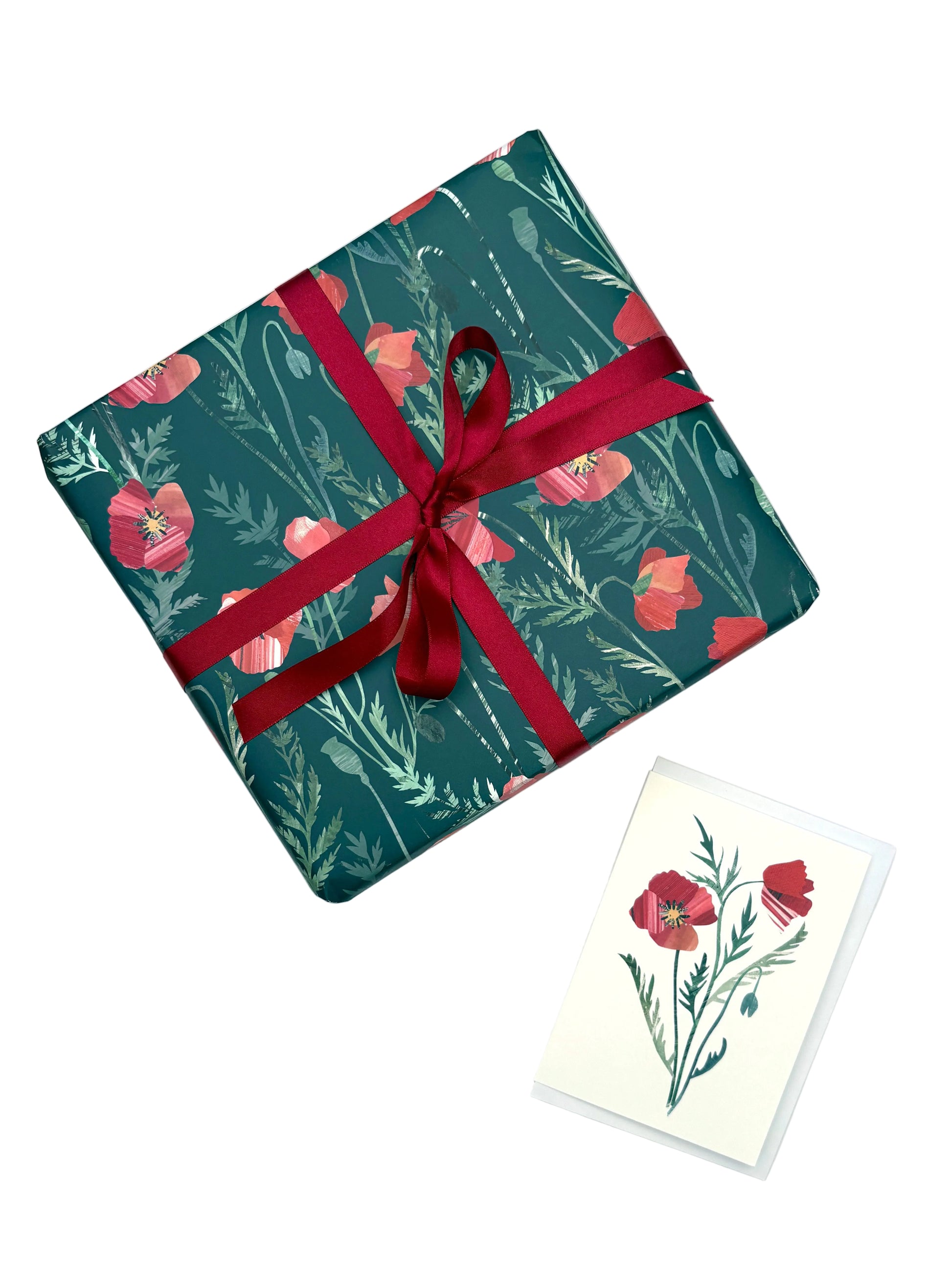a present wrapped in the Poppies Gift wrap has been placed on a white background with a matching poppy greeting card.