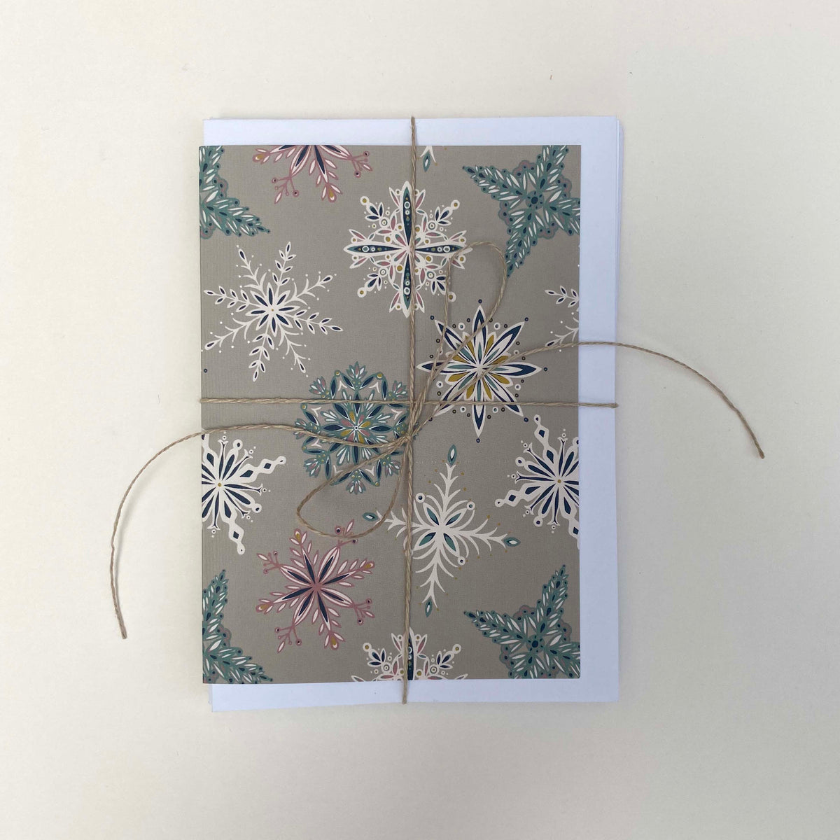 A pack of grey Snowflake cards and envelopes have been tied with twine and placed on a white background.
