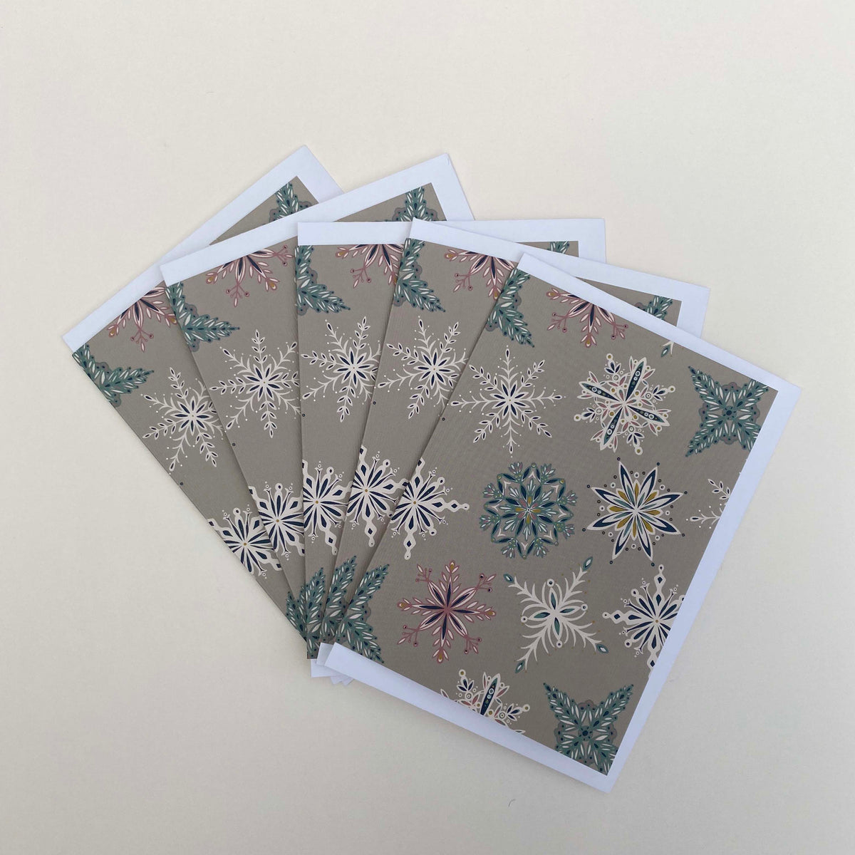 A pack of 5 grey Snowflake cards and envelopes have been fanned out and placed on a plain white background.
