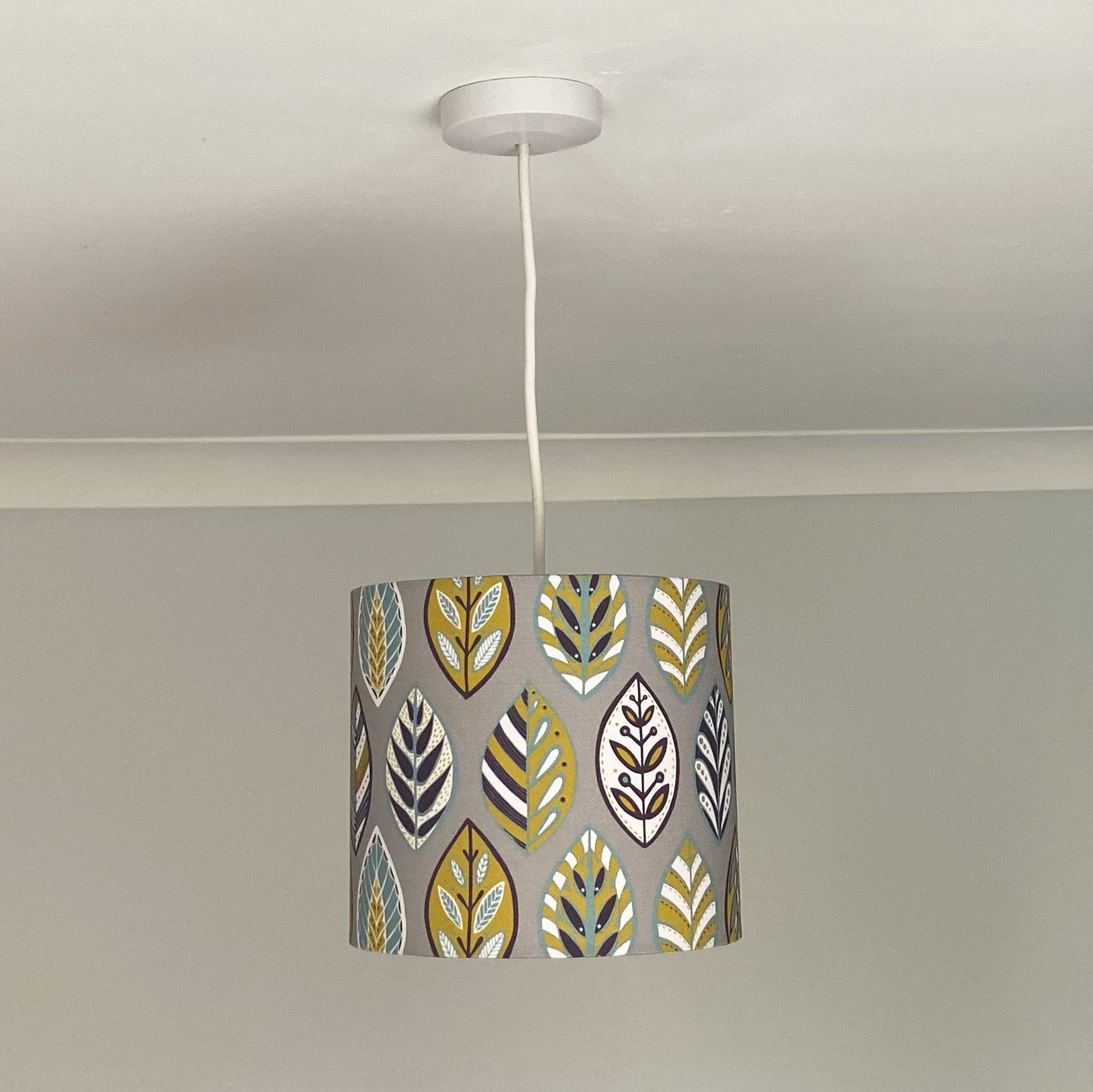 Small Grey Oak leaf Lampshade with a ceiling pendant fitting. This pattern features Blue, Yellow, White and Aubergine leaf Pattern in a Skandinavian style on a Grey background.