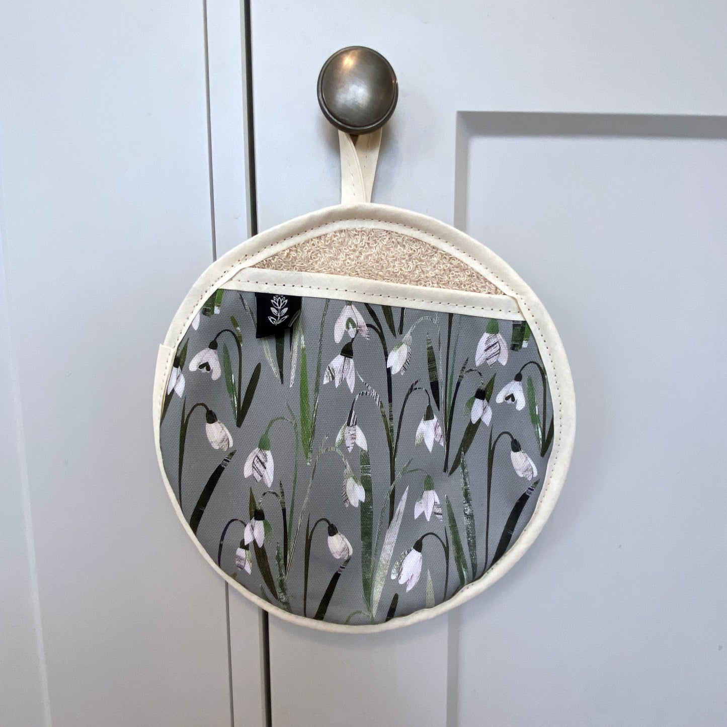 Snowdrops pot grab has been hung on a grey kitchen cupboard door handle with its cream hanging loop.