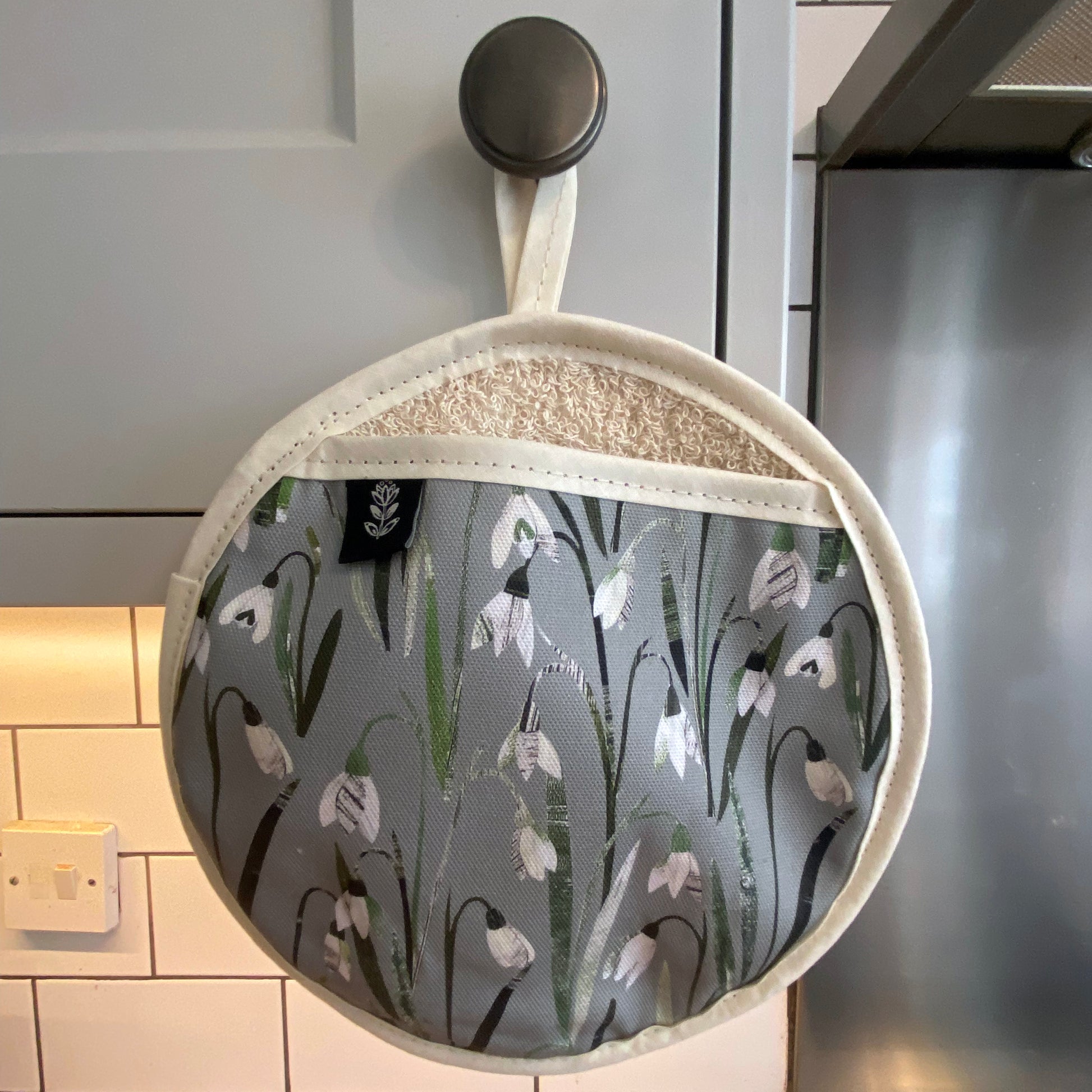 The Snowdrops pot grab has been hung up on a kitchen cupboard door handle.