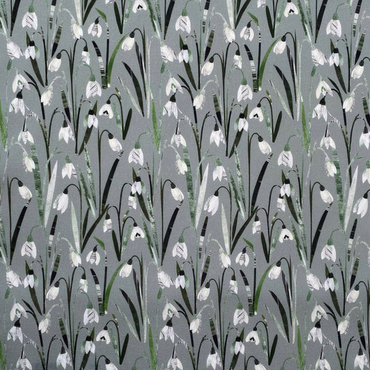 Cream and white Snowdrop flowers with green leaves on a soft sage green cotton background.