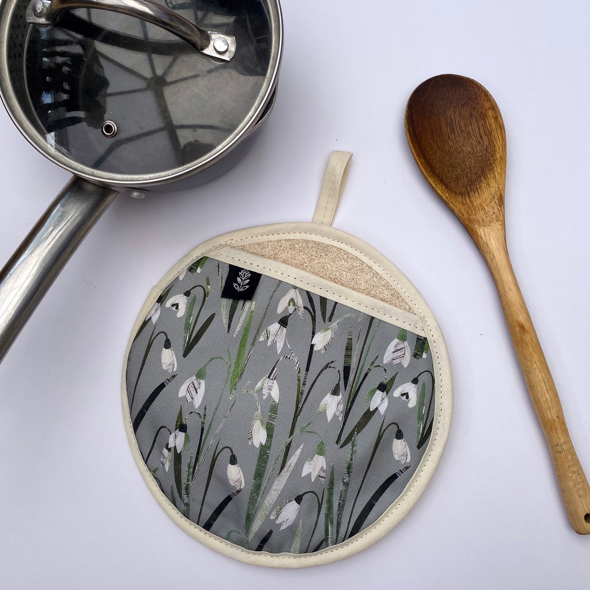 Snowdrops pot grab placed on a white background with a wooden spoon and small saucepan.