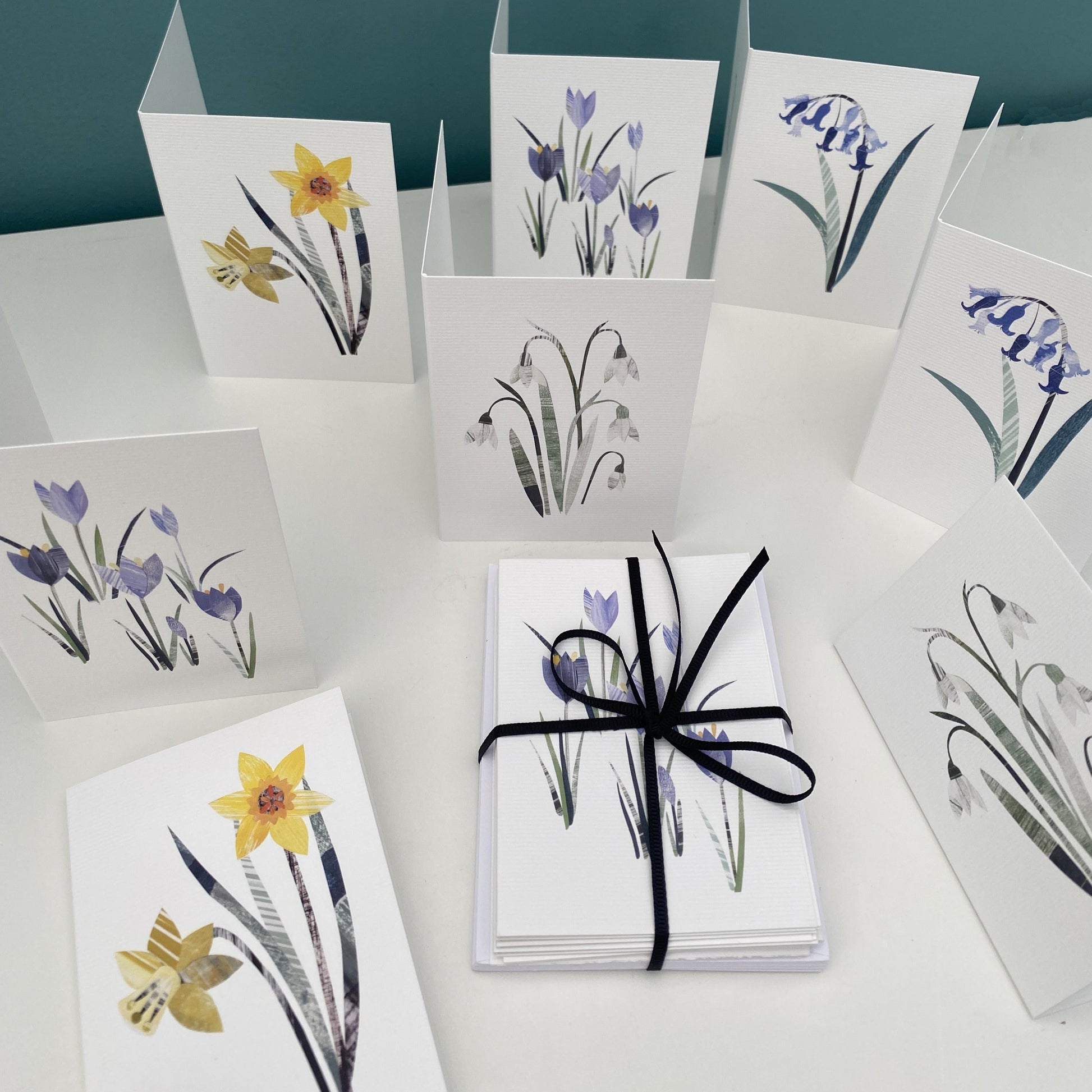 Pack of 8 mini Notecards and envelopes featuring spring flowers.  They have been put on a white shelf. Some are laying down and some are stood up open on the shelf.