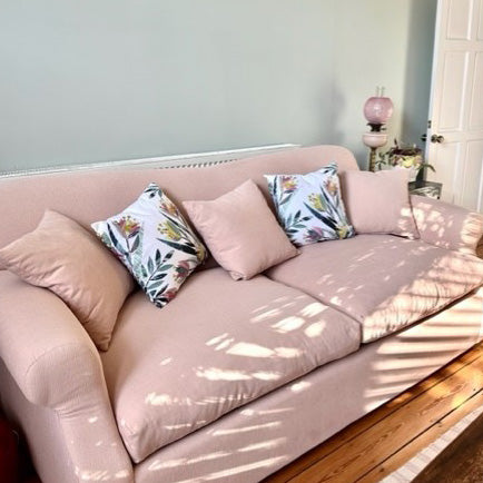 Photograph of two tulip Cushions on a Pale Pink Sofa with coordinating plain pink cushions.