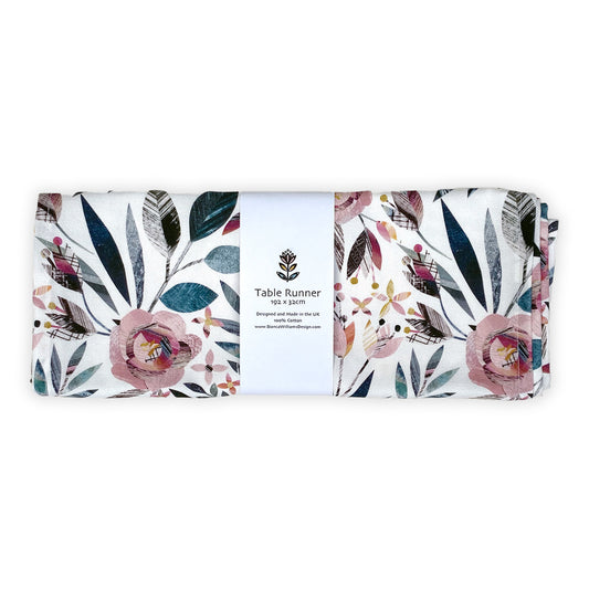 A Summer Floral Table Runner has been folded and packaged in a branded white belly band and placed on a plain white background.