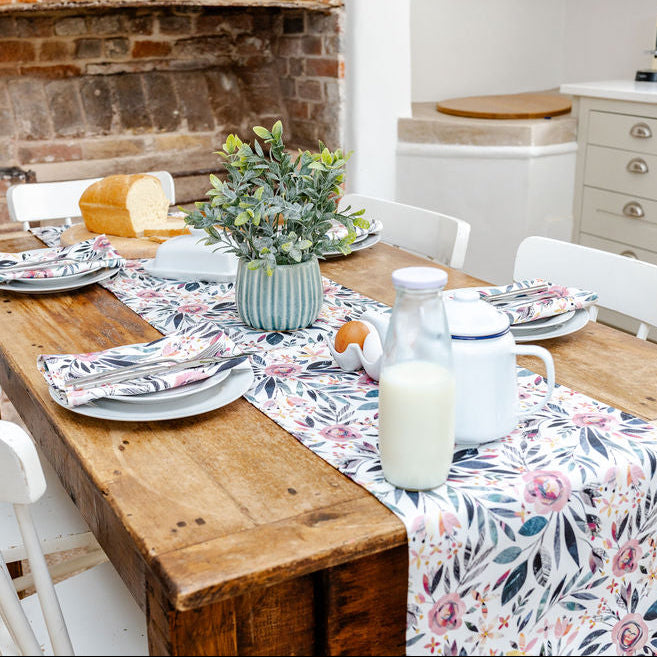 Dining table set with plates, cutlery, and a Summer Floral table Runner and matching Napkins in a cream kitchen.