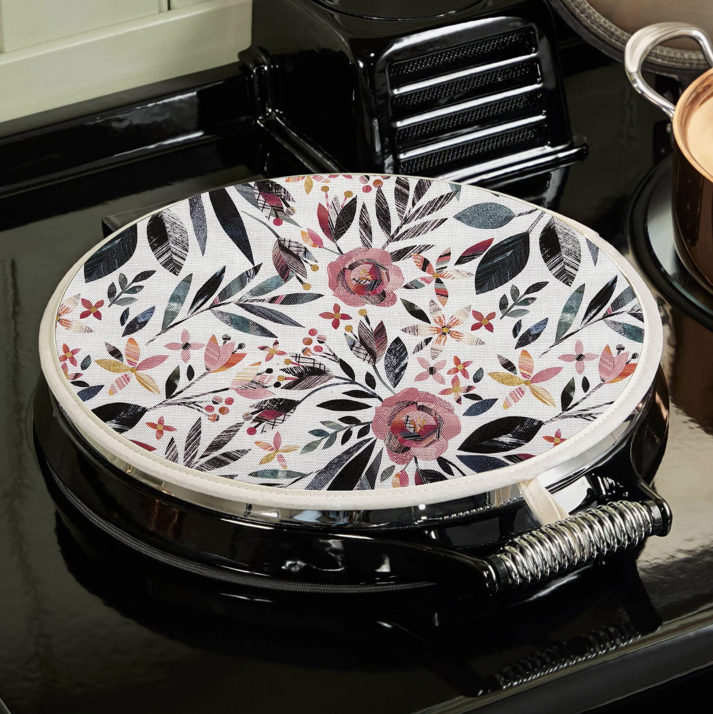 A summer floral Aga topper has been placed on a black AGA.  you can see how the hanging loop hooks onto the top of the hob.