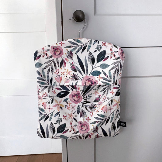 A Summer Floral peg bag featuring a pink and green pattern has been hung on a pale grey kitchen door knob.