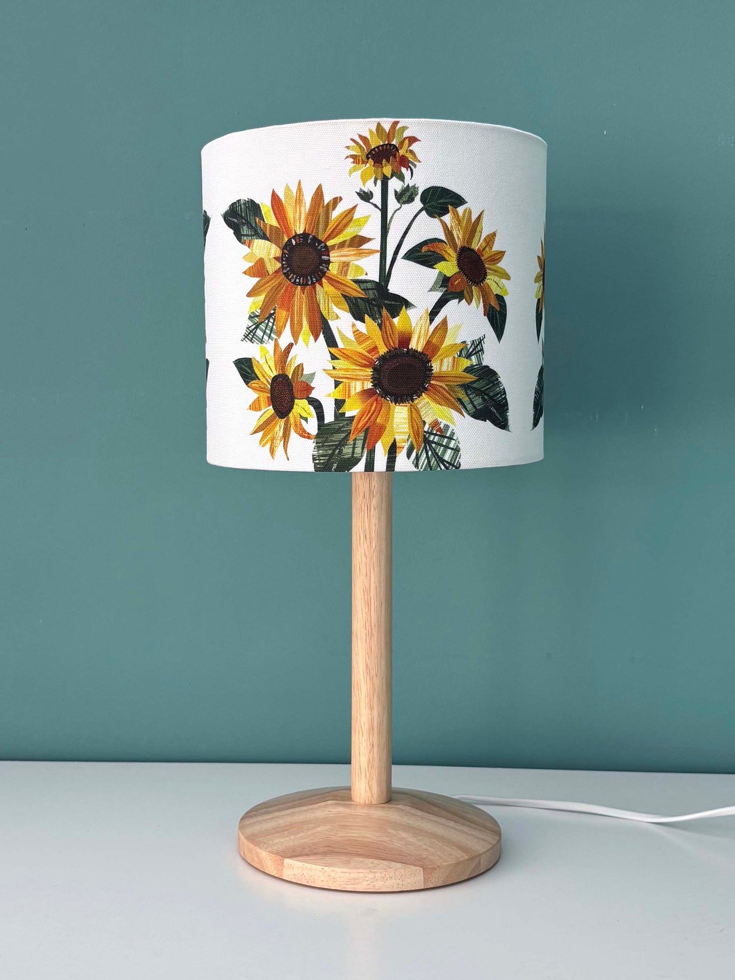 Table lamp with sunflower-patterned shade against a teal background