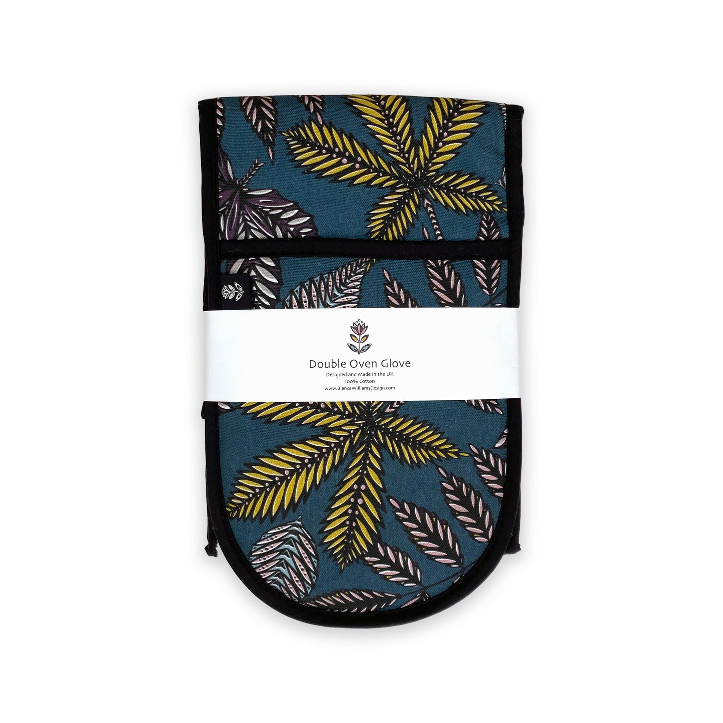 Teal Forest Floor Oven Gloves have been folded and packaged in a branded belly band and they have been placed onto a plain white background.  A Branded label can also be seen sewn into the seam of the oven Gloves.  The pattern features different shaped leaves in an all over pattern.