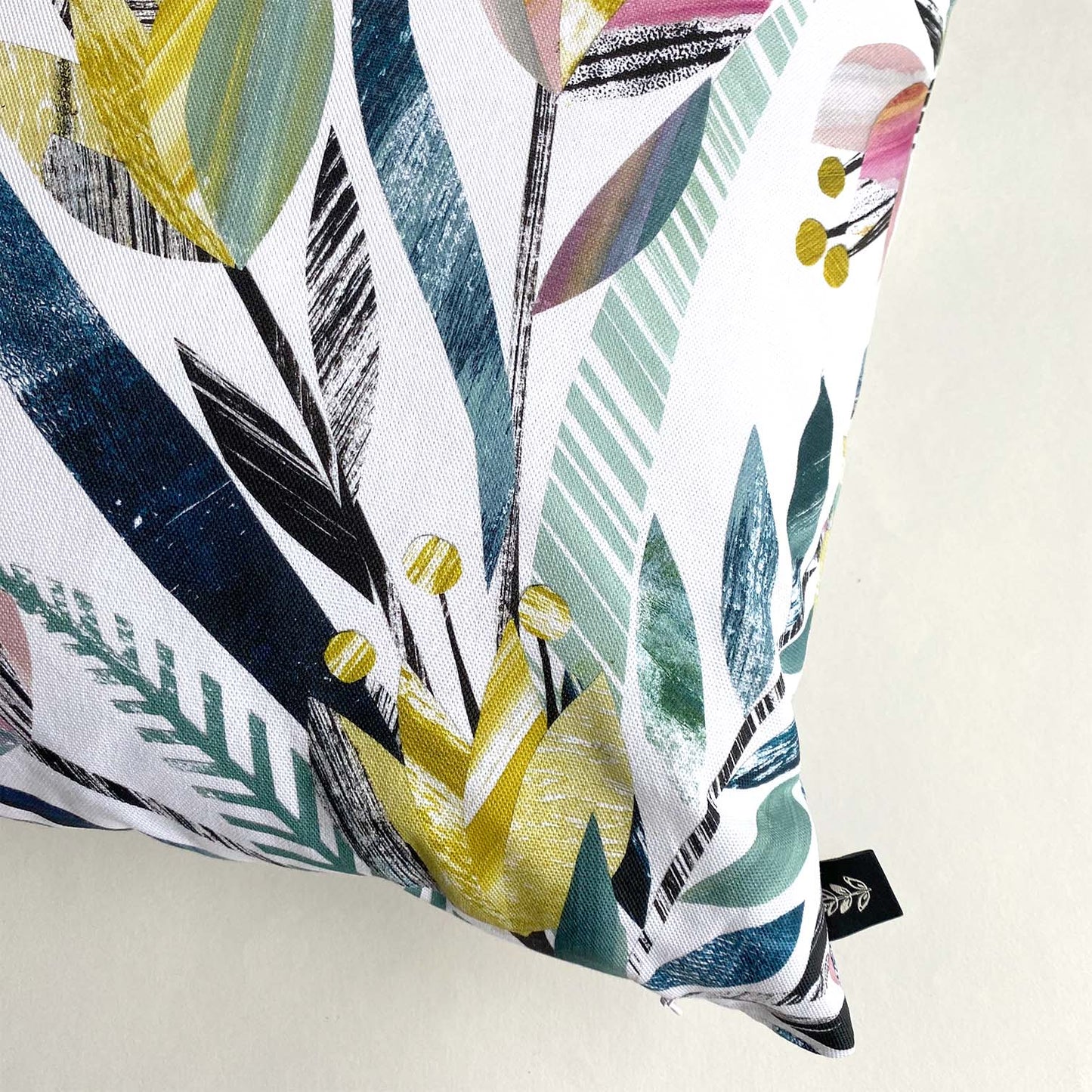 Corner of the Tulips Cushion, showing details of the Yellow, Pink and green tulip print and a Bianca Williams Design Brand label.